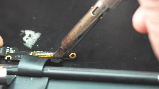 Close-up of technician soldering video connector during precise laptop motherboard repair