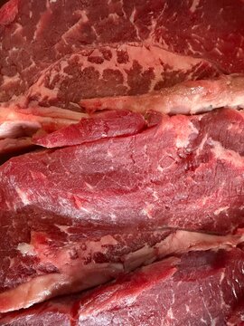 Raw beef steak close up showing vibrant red muscle tissue and intricate marbling patterns, highlighting freshness, quality, and rich protein content for cooking