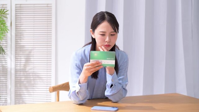 通帳を見て悩む女性