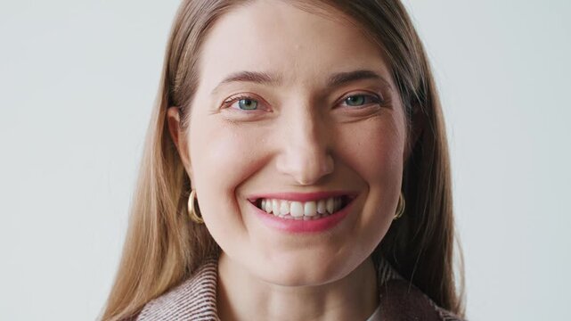 Close up portrait of confident Caucasian woman looking at camera with calm expression. Young female wearing gold earrings. Natural beauty minimal makeup clean background professional headshot.