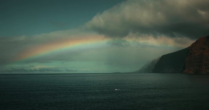 Bright Rainbow Over Ocean Waters and Volcanic Cliffs in Tenerife Spain