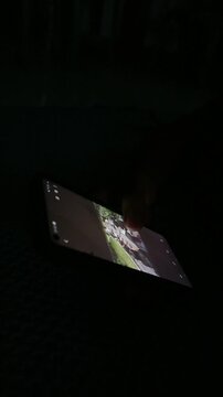 A person viewing a photograph on a smartphone screen in a dark room.