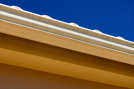 Close-up of a dirty gutter system against a clear blue sky
