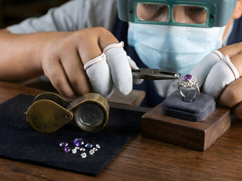 Master Jeweler Setting Small Gemstones into Amethyst Ring | Professional Jewelry Craftsman Working with Pliers and Loupe | Jeweler Workshop Setting Accent Diamonds in Silver Ring | Precision Jewelry 
