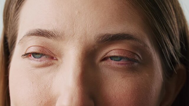Detailed portrait Caucasian woman looking into camera with green eyes and gentle smile. Close up female face showing natural beauty and confidence indoors. Human emotions and wellness.