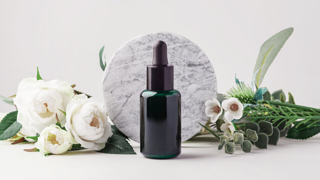 Dark green essential oil dropper bottle mockup with   marble podium and white roses and green leaves







, natural skincare, wellness, and aromatherapy
