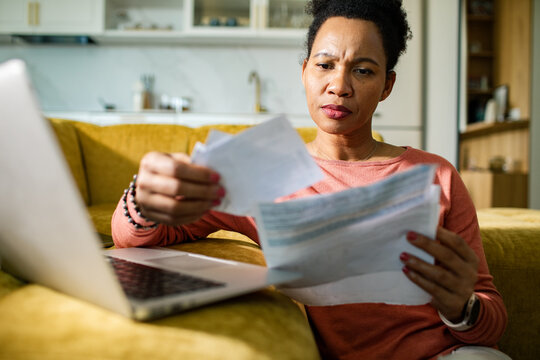 Woman reviewing bills at home with laptop