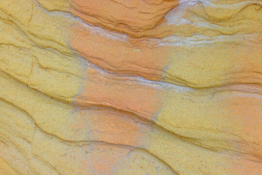 Aerial view of the textured sandstone rock formations of Karynzharyk, showcasing natural erosion patterns and vibrant orange and yellow layers in Karakiya District, Mangystau Region, Kazakhstan.