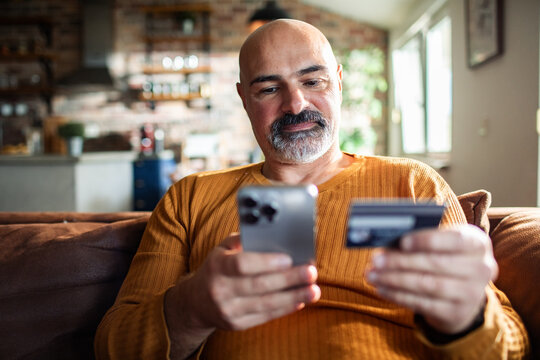 Man making online payment with credit card and smartphone at home