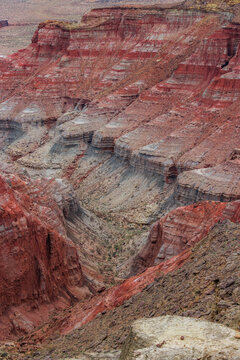 Aerial view of Karynzharyk canyon with striking red and grey layered rock formations, steep cliffs, and rugged desert terrain in Karakiya District, Mangystau Region, Kazakhstan.