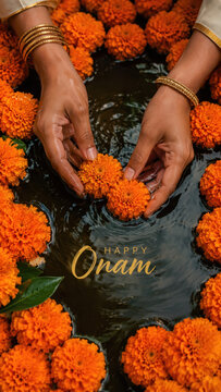 Hands placing orange marigold blossoms in dark water, happy onam greeting with gold bangles, floral offering ritual, south indian harvest festival, temple pond ripples, festive typography