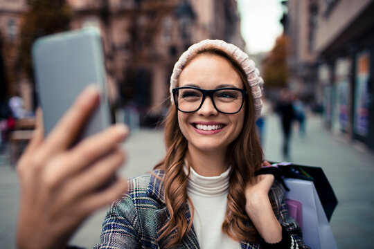 Smiling woman taking selfie on urban shopping street