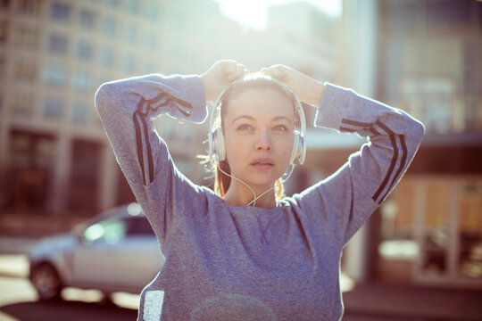 Young woman runner with headphones on city street at sunrise