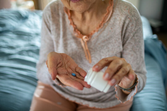 Senior woman taking medication in home bedroom