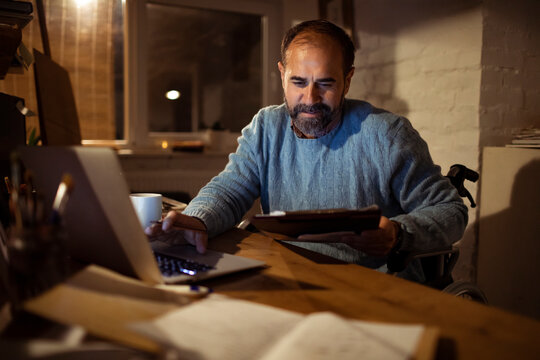 Man in wheelchair working late in home office