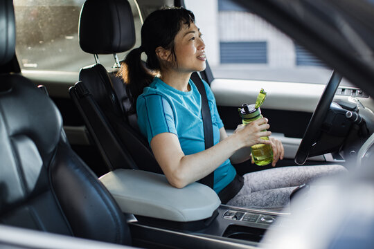 Woman with reusable water bottle in parked car