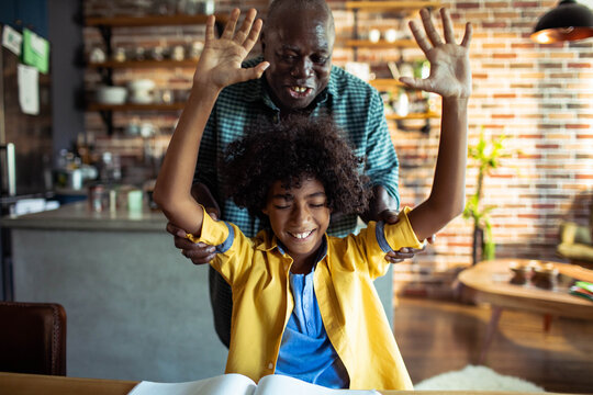 Grandfather and grandson celebrating homework success in kitchen