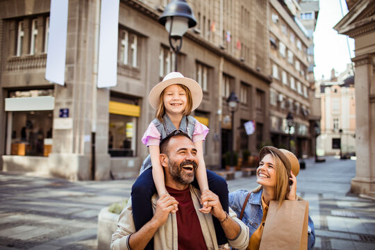 Father carrying daughter as family shops on city street