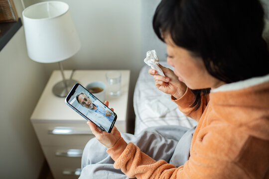 Sick woman having virtual doctor consultation at home in bedroom