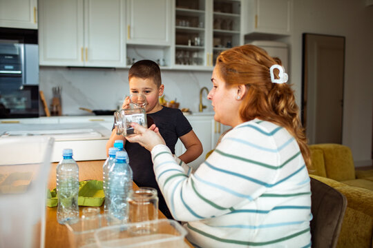 Mother and son sorting recyclables in home kitchen