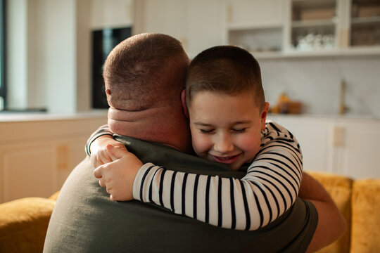 Loving father hugging happy son in kitchen