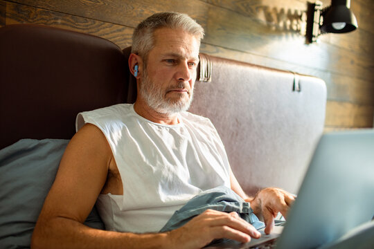 Mature man using laptop in bed at home