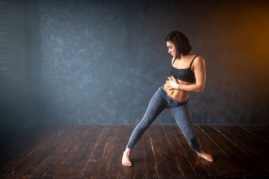 Flexible athletic girl dances in the dark studio room