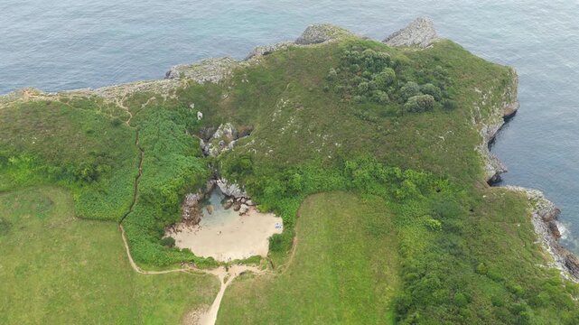 Aerial View of the Unique Inland Tidal Beach of Playa de Gulpiyuri Surrounded by Green Cliffs and Meadows in Asturias, Northern Spain