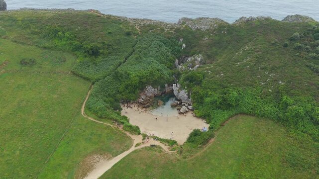 Aerial View of the Unique Inland Tidal Beach of Playa de Gulpiyuri Surrounded by Green Cliffs and Meadows in Asturias, Northern Spain