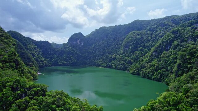 Cinematic aerial drone footage overlooking the famous Lake of the Pregnant Maiden (Dayang Bunting Lake) in Langkawi, Malaysia, surrounded by lush rainforest and limestone mountains.