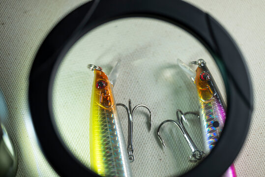 Close up view of minnow lures under magnifier glass The Concept of tackle selection and craftsmanship