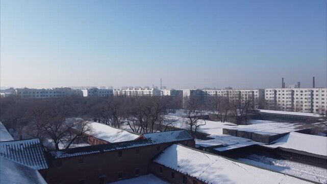 Aerial view of the historic Site of Unit 731 museum complex with snow-covered rooftops and surrounding urban buildings in Harbin, Heilongjiang, China.