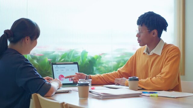 Diverse business colleagues discussing financial data and roadmap strategy on tablet computer in modern office	