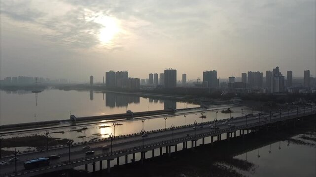 Aerial view of a bridge spanning the river with the city skyline of Luoyang in the background during sunset in Luoyang, Henan, China.