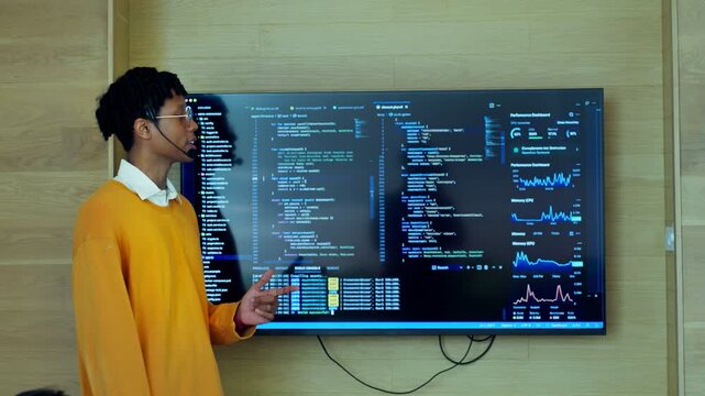 Young developer presenting code and analytics dashboard on large monitor. suitable for it training, software engineering, and tech startup campaigns.