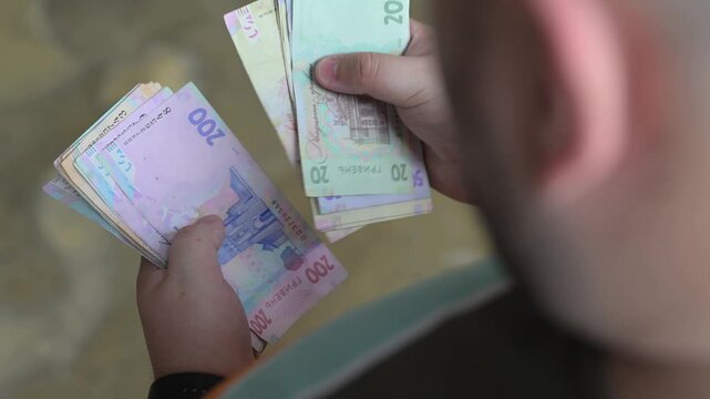 Man hands counting stack of mixed Ukrainian hryvnia banknotes close up.