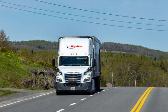 Gaspesie, Canada, 30 May 2026 : A white Ryder semi truck drives on a two-lane road through a rural landscape under a clear sky.