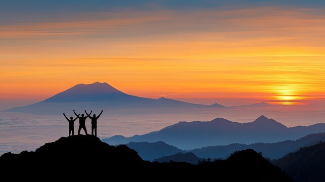 Silhouette of three people on mountain peak at sunrise, holding raised fists, team success, motivation and teamwork concept over sea of clouds