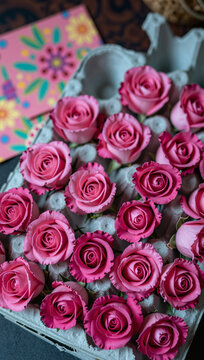 A close-up of pink roses in a box, with colorful background elements.
