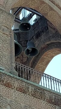 Historic Church Bell Tower and Bronze Bells Architecture. Scenic low angle view of ancient stone bell tower architecture with hanging church bells, ideal for cultural tourism, history, and heritage pr