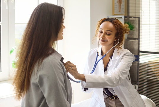 Doctor uses stethoscope for patient examination. A friendly physician checks heart and lungs at a bright clinic, ensuring accurate diagnosis and care. Core healthcare trust and care concept.