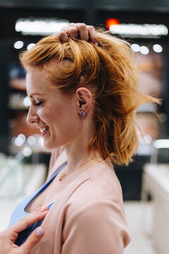 Sophisticated female shopper examining expensive diamond earrings and necklace while making purchasing decisions inside an upscale retail establishment.