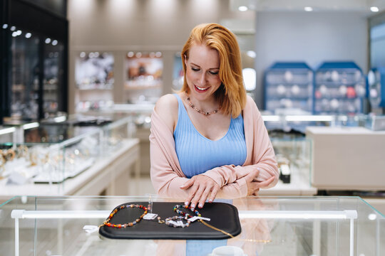 Sophisticated happy woman exploring and selecting precious accessories inside a high-end jewelry store.