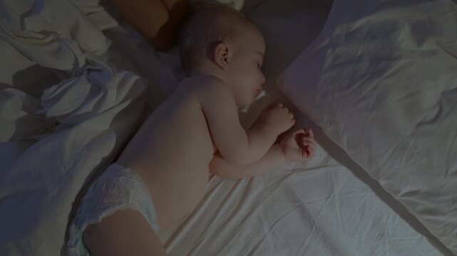 Infant sleeping peacefully on a bed with white sheets, soft light illuminating the scene, showcasing a serene and cozy atmosphere in a domestic setting