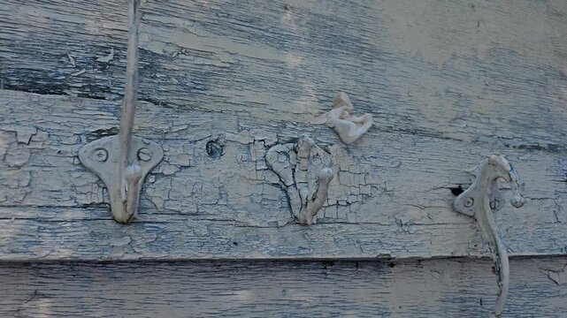 Old rusty metal hooks mounted on a weathered wooden wall showing vintage hardware and aged rustic craftsmanship
