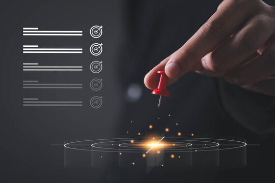Business hand placing a red push pin on a digital target, symbolizing goal setting, strategic planning, project management, business objectives, success, focus, productivity, and achievement.