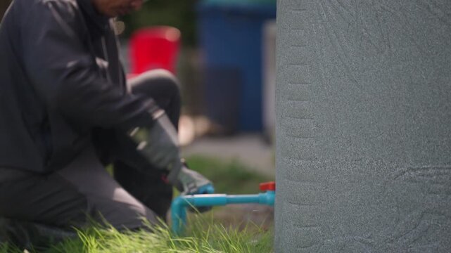 Worker Servicing Outdoor Household Water Supply Plumbing System