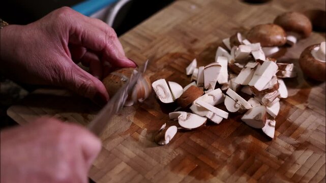 Woman's hands slicing portobello mushrooms on cutting board.