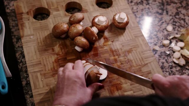 Woman's hands slicing portobello mushrooms on cutting board.