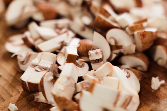 Freshly chopped portobello mushrooms on wooden cutting board closeup.
